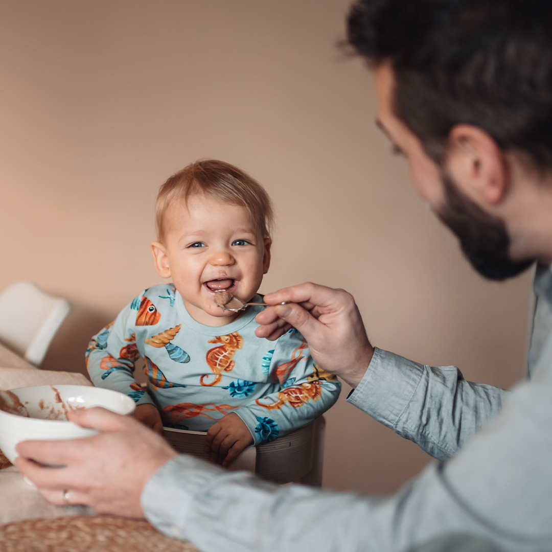 Father feeding baby porridge