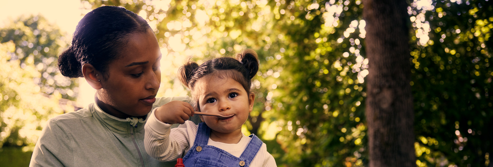 Mother and child with spoon outdoors